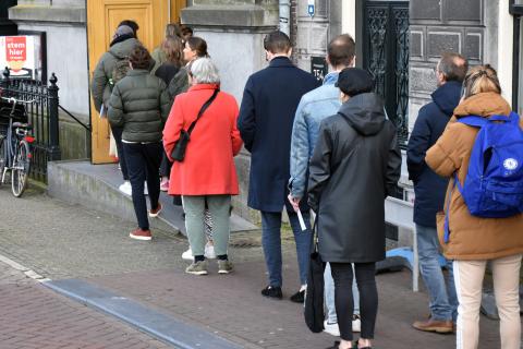 Mensen staan achter elkaar in de rij. Ze dragen warme jassen