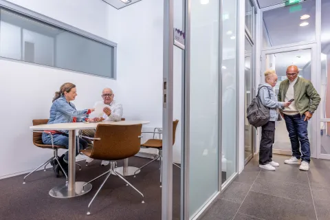 Mensen in gesprek met elkaar op de gang en in een kantoorruimte