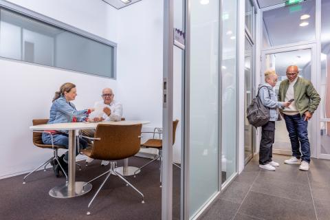 Mensen in gesprek met elkaar op de gang en in een kantoorruimte