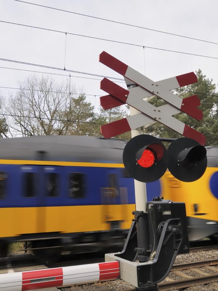 Foto van een spoorwegovergang waar een trein langs komt