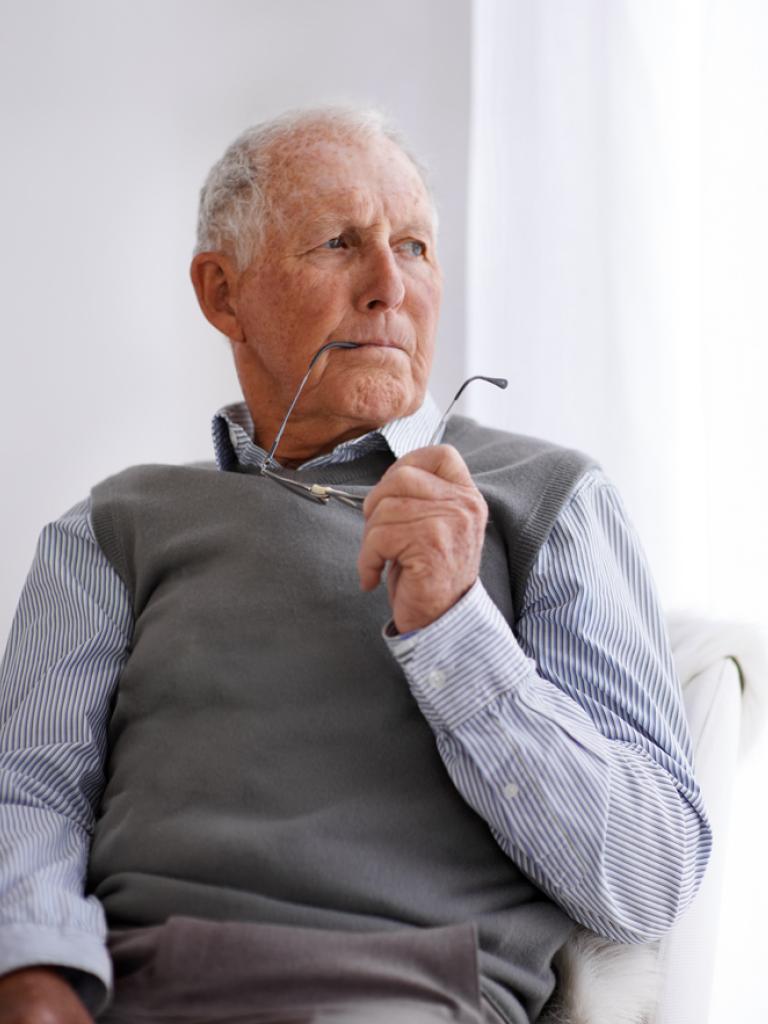 Foto van een oudere man met bril in zijn hand