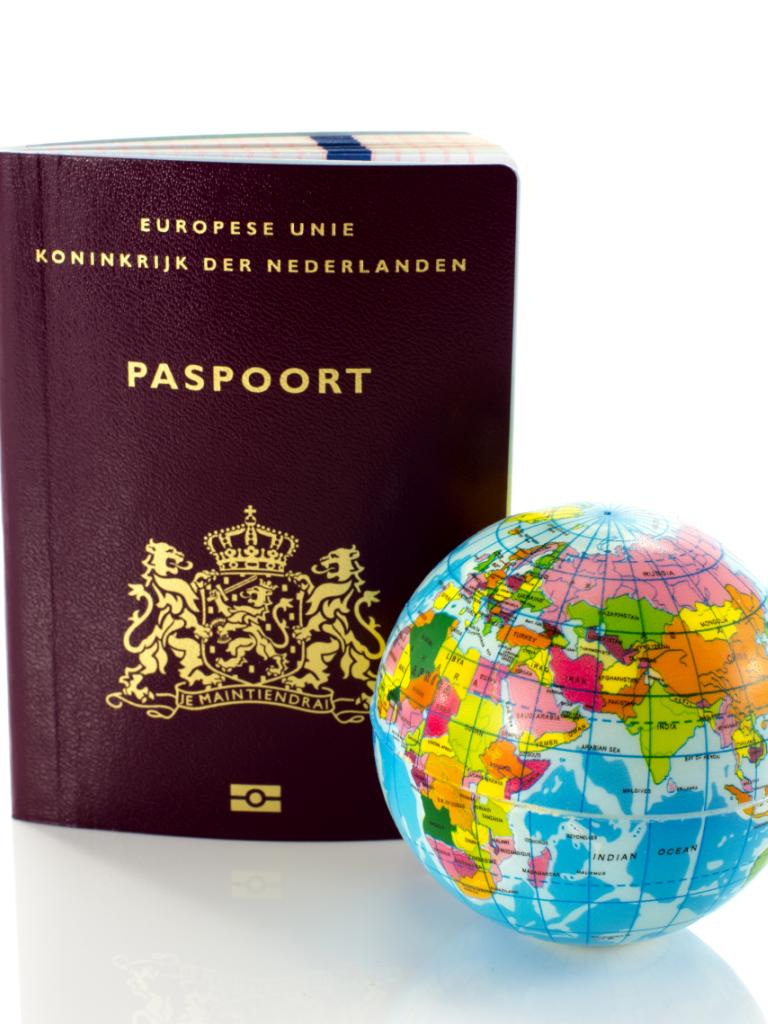 Foto van een Nederlands paspoort en wereldbol