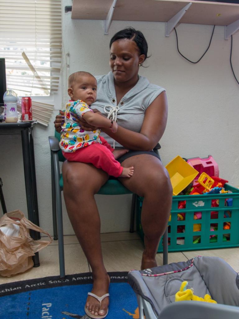 Een Caribische vrouw houdt een klein kind vast op haar schoot