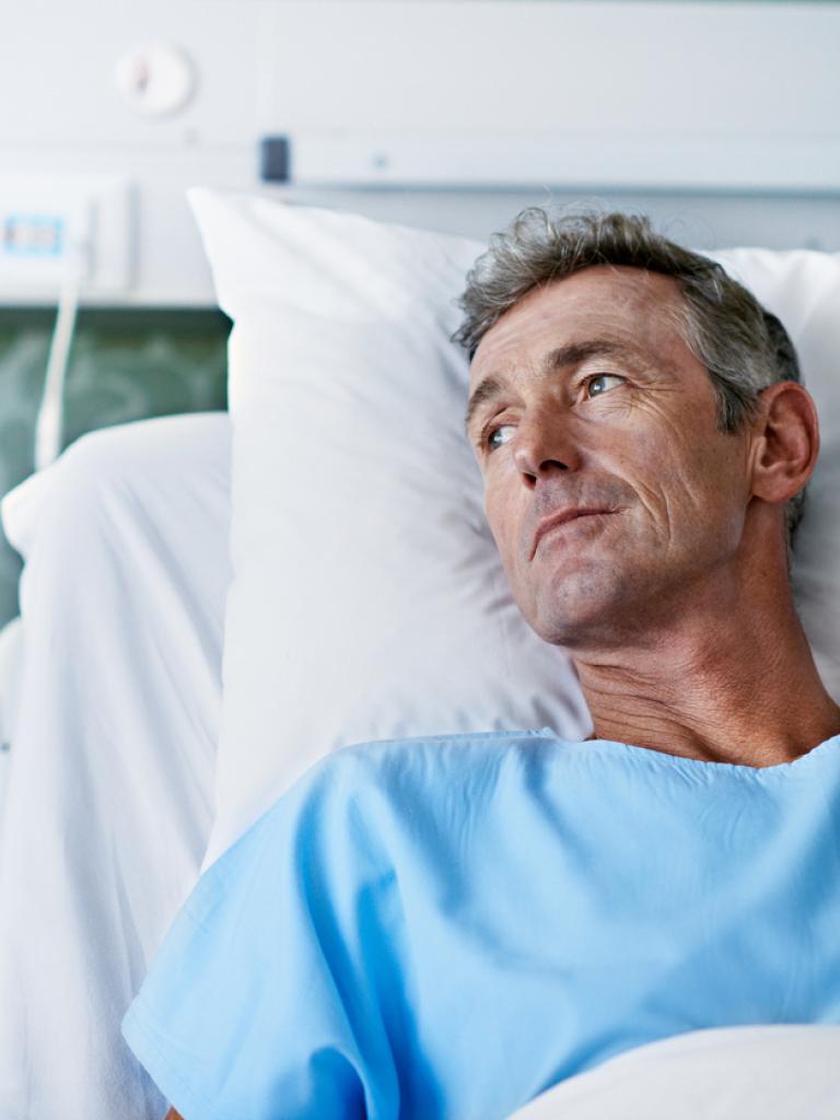 Man in ziekenhuisbed kijkt weemoedig uit het raam
