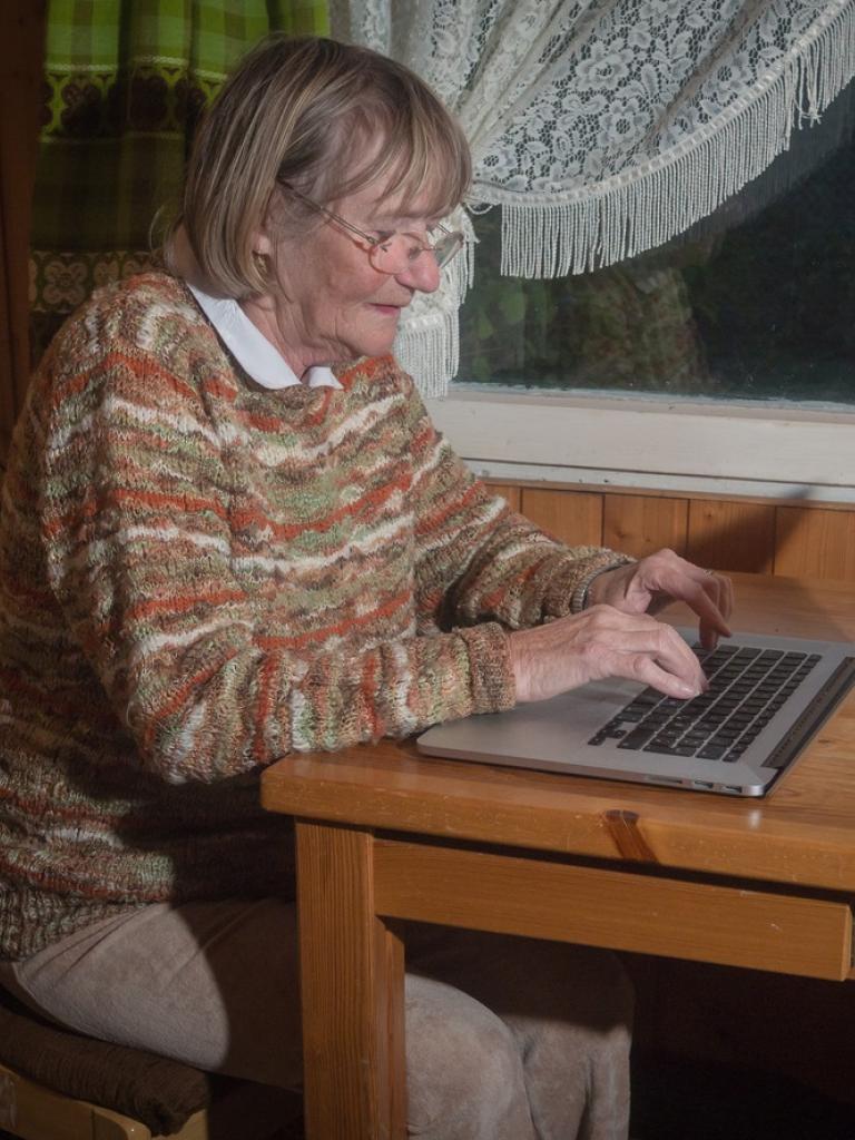 vrouw achter laptop aan keukentafel