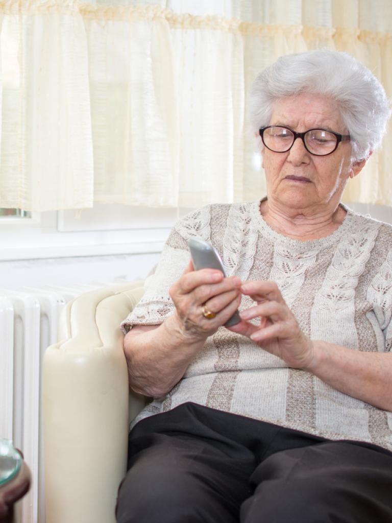 Bejaarde vrouw met telefoon in haar hand
