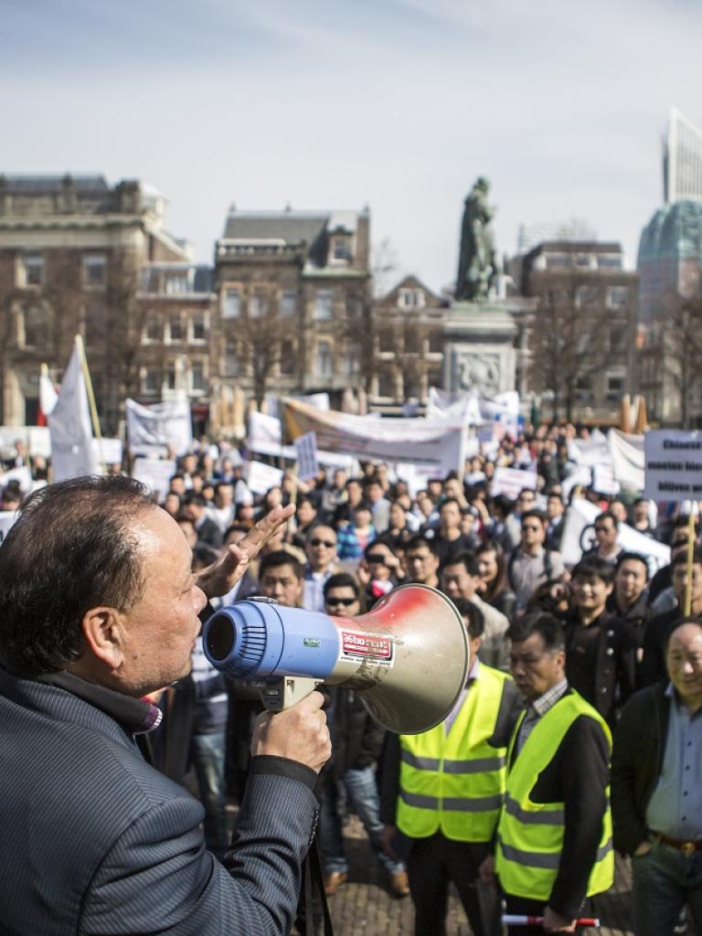Man met megafoon praat tegen menigte tijdens demonstratie in Den Haag