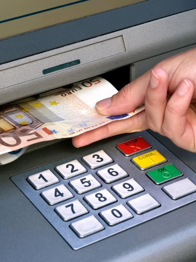 Een hand haalt een briefje van 50 euro uit een pinautomaat
