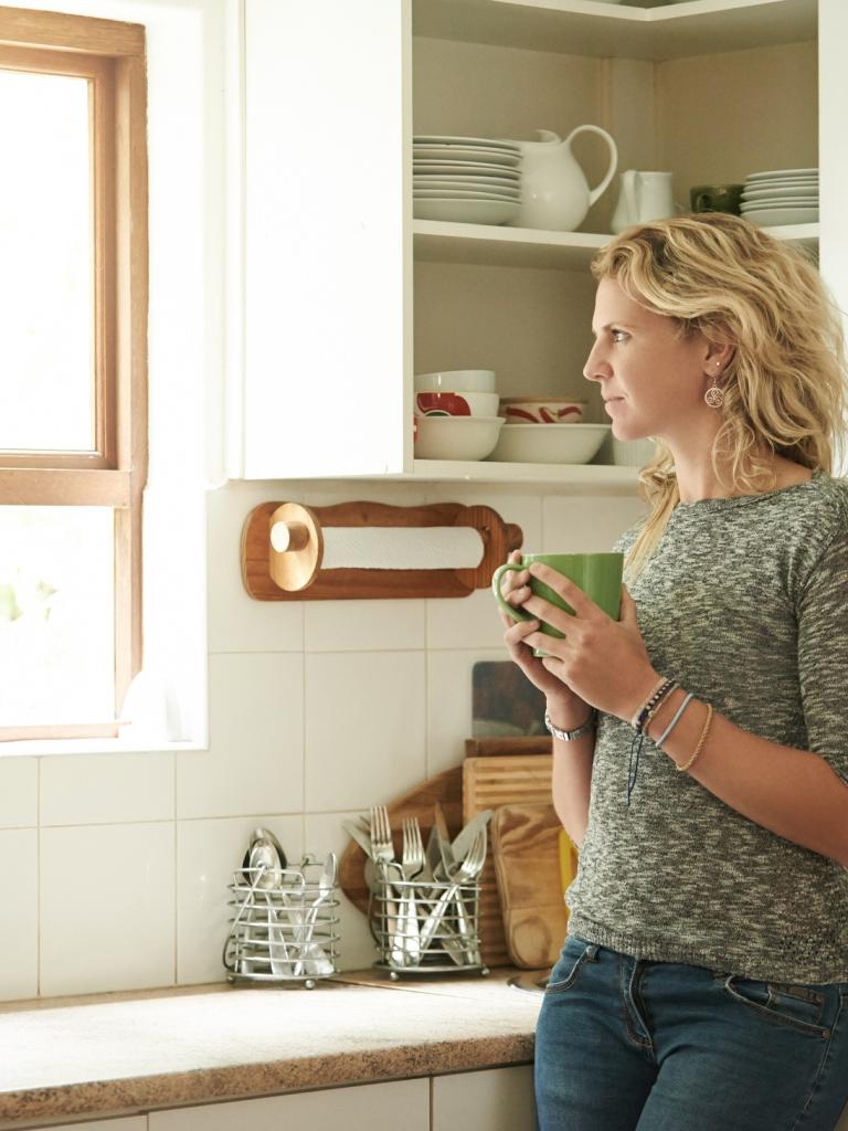 Vrouw in de keuken met een kop koffie