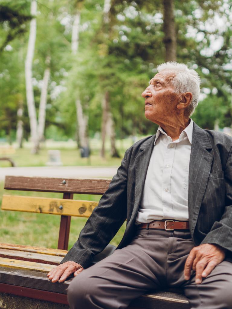 Foto van een senior man op een bankje in het park