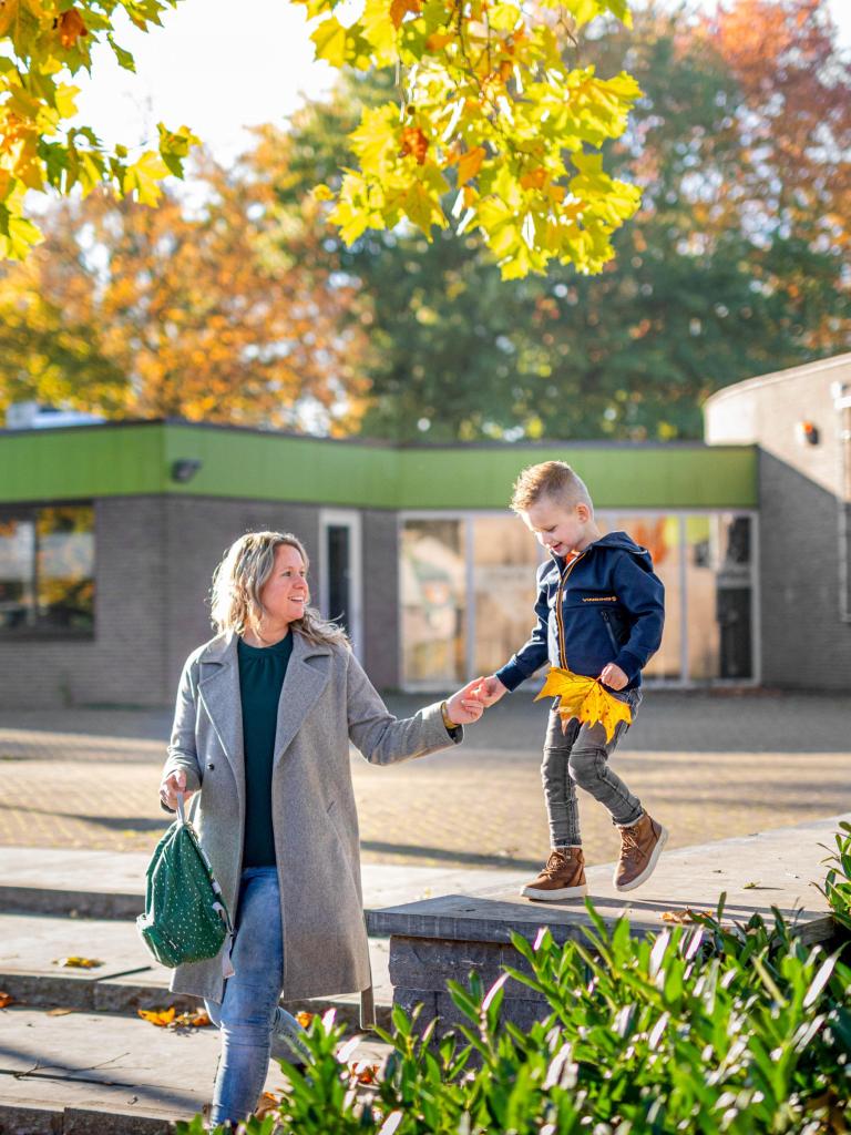 Moeder loopt hand in hand met haar zoontje voor een openbaar gebouw