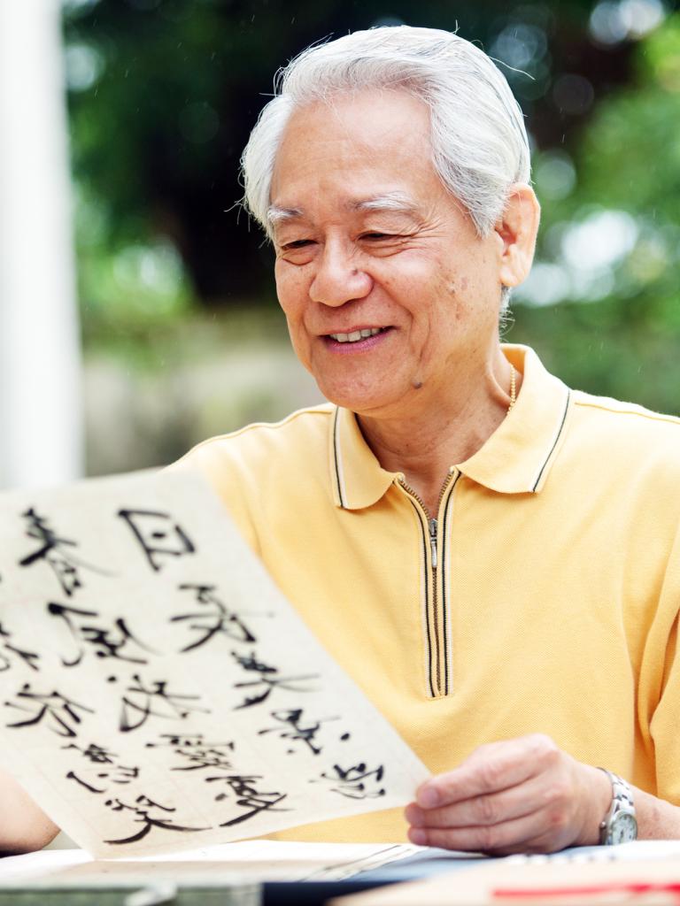 Aziatische man zit aan tafel en leest kalligrafie