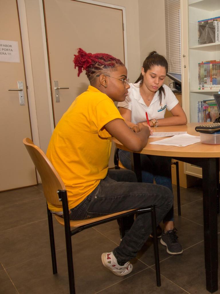 Drie Caribische studenten zitten aan tafel en zijn samen aan het studeren