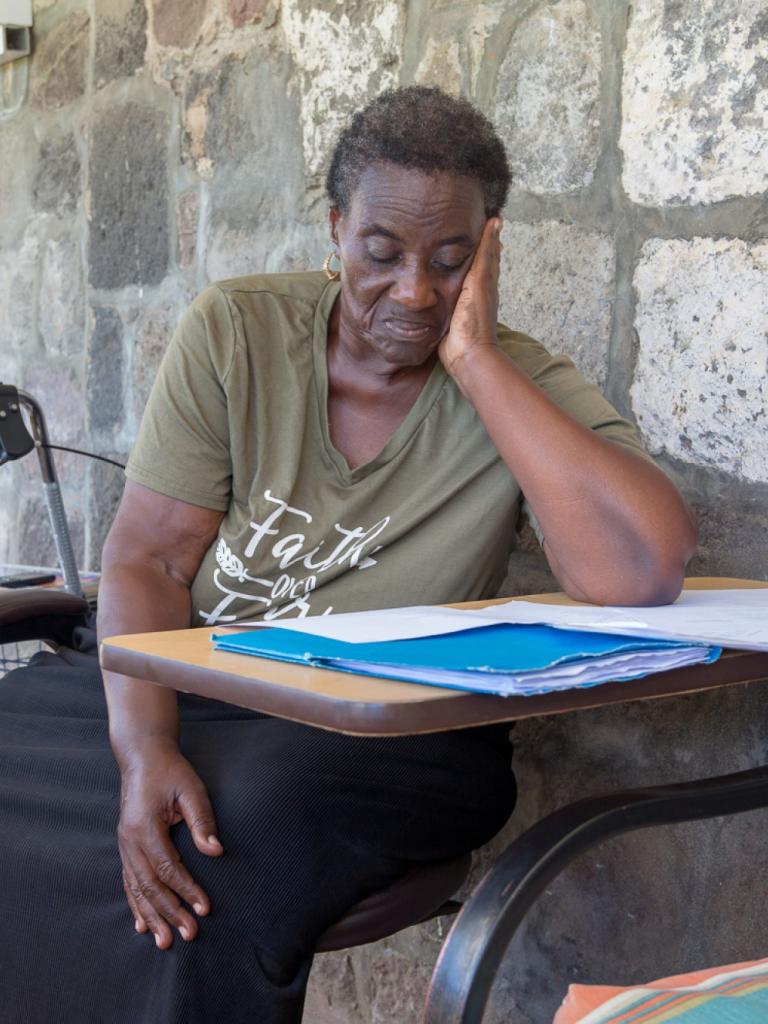 Vrouw zit aan tafel en leest document (Caribisch NL)