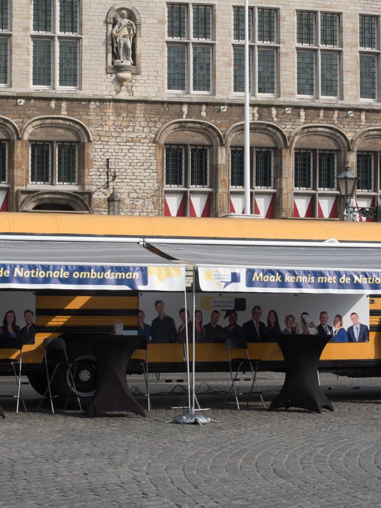 Gele geparkeerde Ombudsbus van de Nationale ombudsman