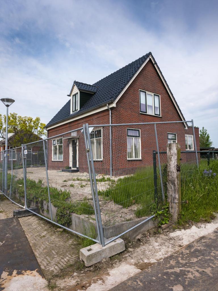 Een huis in Groningen waar bouwhekken omheen staan.