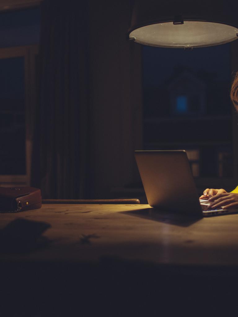 vrouw zit met haar laptop in donkere ruimte