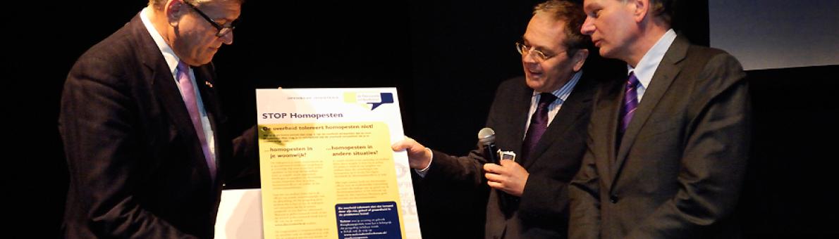 Nationale ombudsman Alex Brenninkmeijer overhandigt de 'Stop homopesten' kaart aan Henk Krol