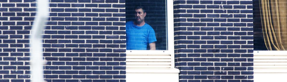 Man in detentie. Hij draagt een blauw shirt