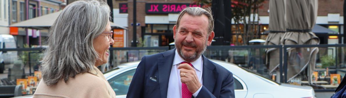 De Nationale ombudsman in gesprek met een vrouw met grijs haar en een beige jas. Links van hen staat een vrouwelijke collega van de ombudsman. De Nationale ombudsman in gesprek met een vrouw met grijs haar en een beige jas. Links van hen staat een vrouwelijke collega van de ombudsman.