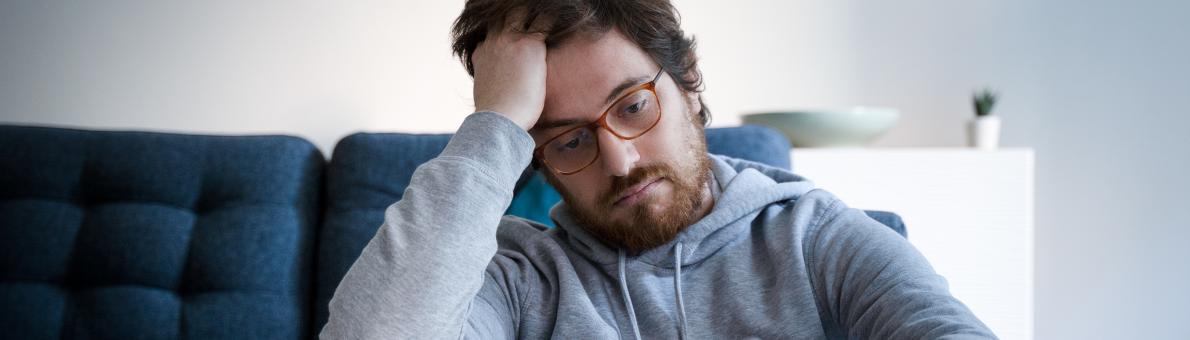 Man zit teleurgesteld op de grond voor zijn bank.