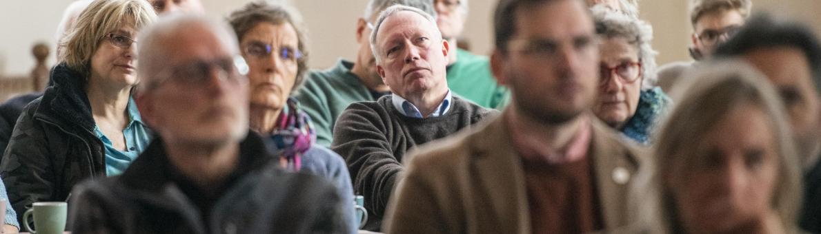 Groep inwoners van Loppersum (Groningen) luistert naar iemand bij een bijeenkomst