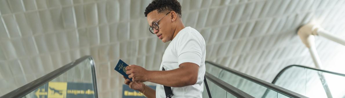 Jonge man op vliegveld kijkt naar paspoort