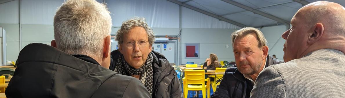 Voorzitter Vluchtelingenwerk Frank Candel en Nationale ombudsman Reinier van Zutphen in gesprek met twee medewerkers van het COA