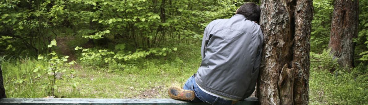 Man op bankje in de natuur