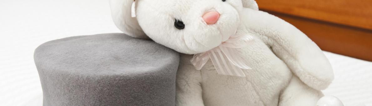 Foto van een wit pluchen konijn naast een grijze hoge hoed