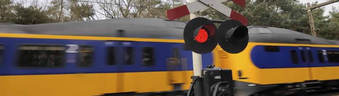 Foto van een spoorwegovergang waar een trein langs komt