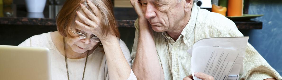 Echtpaar zit gebogen over laptop en brieven