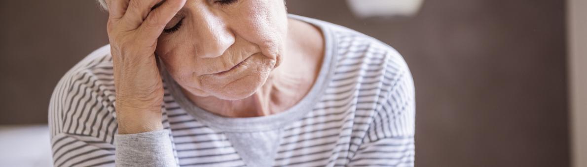 Foto van een vrouw met haar ogen dicht en haar hand tegen haar voorhoofd