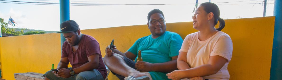 Three people sitting on a bench and talking to each other at Bonaire.