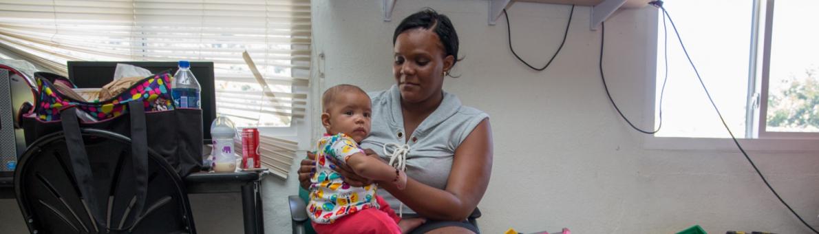 Een Caribische vrouw houdt een klein kind vast op haar schoot