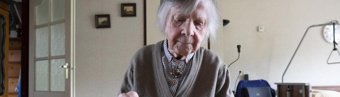 Oudere vrouw smeert een boterham thuis aan tafel