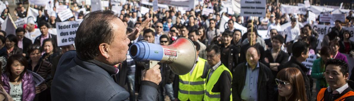 Man met megafoon praat tegen menigte tijdens demonstratie in Den Haag