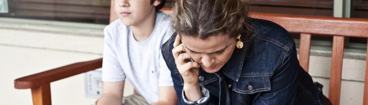 Vrouw en zoon zitten op een bankje te bellen