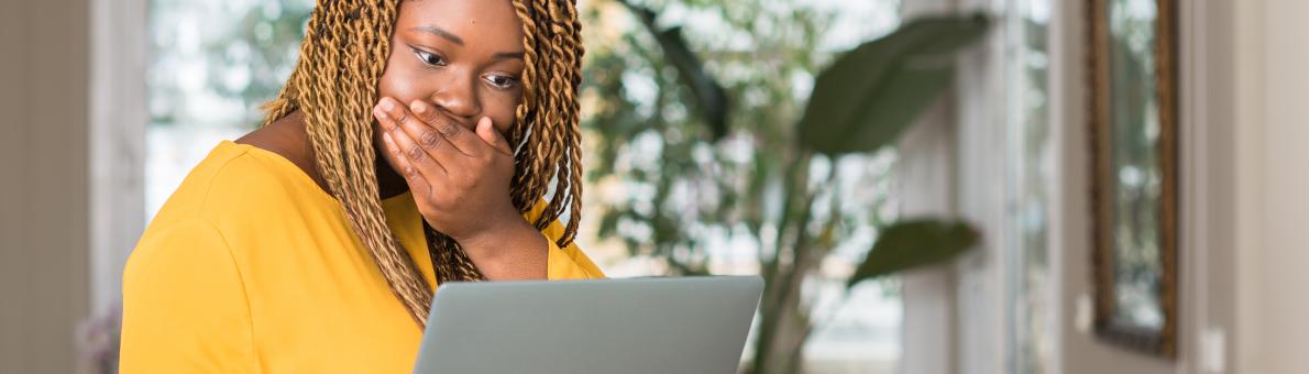 Verbaasde vrouw met laptop in haar hand