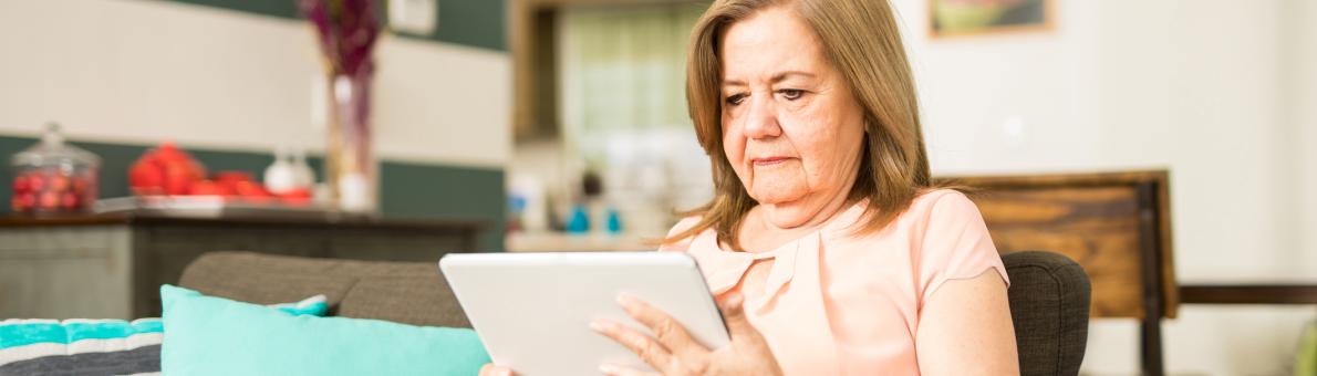 Senior vrouw met een tablet op de bank