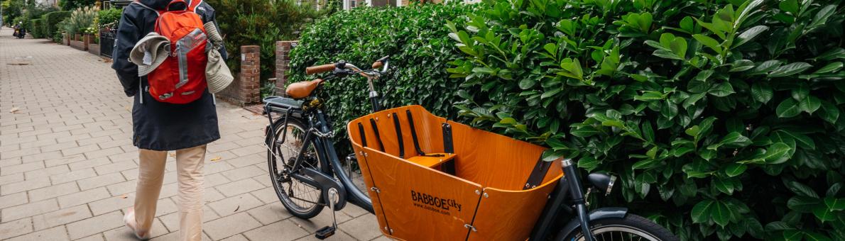 Vrouw loopt langs bakfiets