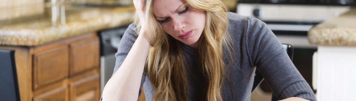 Vrouw met een stapel brieven aan de keukentafel