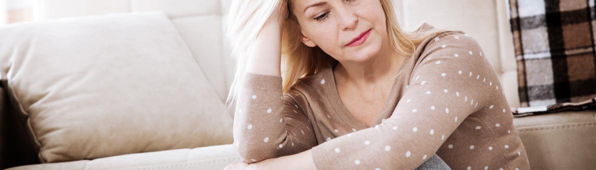 Vrouw met blond haar kijkt al zittend op de grond bezorgd voor zich uit