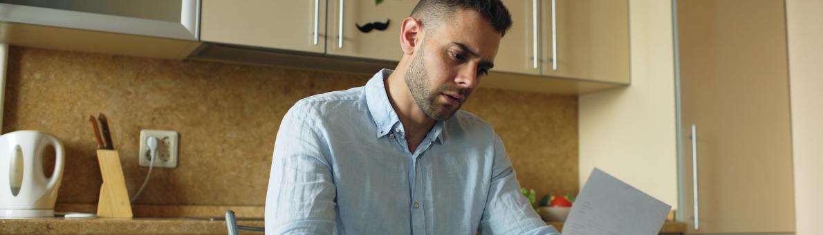 Man leest brief aan tafel in keuken Man leest brief aan tafel in keuken