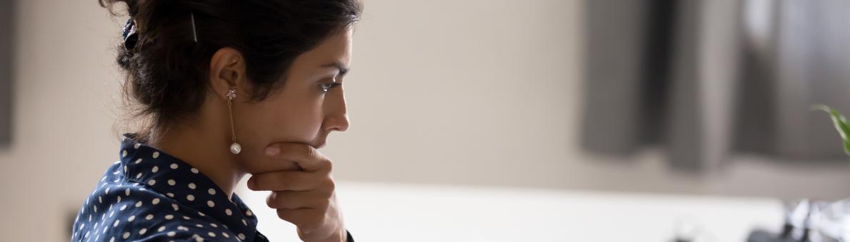 Mevrouw met papieren en telefoon voor zich achter de laptop