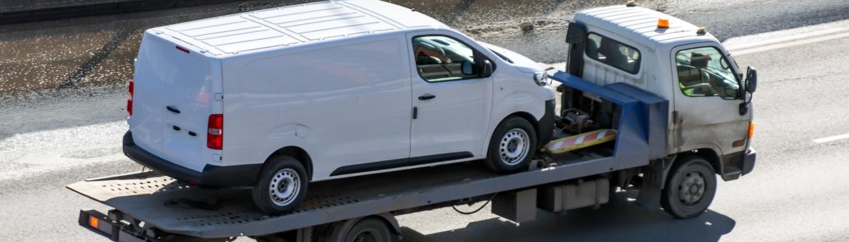 Een witte bestelbus die wordt weggesleept op een vrachtwagen