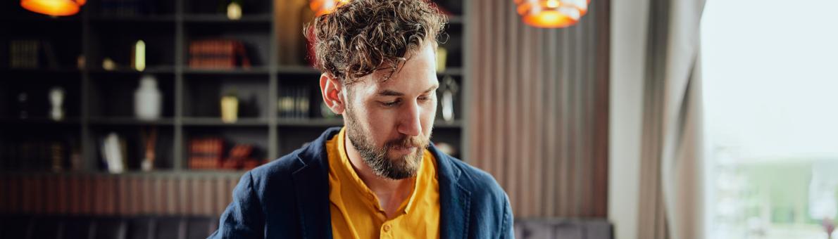 Man met kop koffie en telefoon in de hand in café