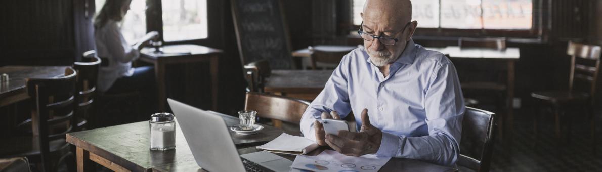 Zzp'er met laptop en papieren voor zich aan het werk in een café