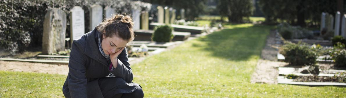Vrouw zit op begraafplaats bij graf van overleden man