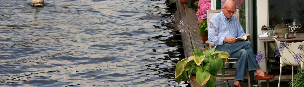 lezende man op terras van woonboot bij artikel over pensioen